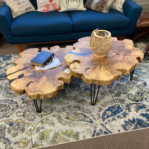 May include: Two wooden coffee tables with live edge tops and black hairpin legs. The tables are on a blue and cream patterned rug in front of a blue sofa with pillows that say "Love is what makes our house a home", "love birds", and "Hello Spring".