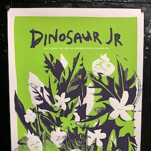 Könnte beinhalten: Ein Konzertplakat für Dinosaur Jr. mit einem leuchtend grünen Hintergrund und dunkelvioletten und weißen botanischen Illustrationen. Der Name der Band steht in großen, dunkelvioletten Buchstaben. Das Plakat enthält auch Datum und Veranstaltungsort des Konzerts.