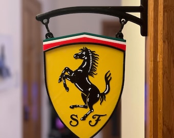 Puede incluir: Un letrero amarillo en forma de escudo con un caballo negro encabritado y las letras "S F" en negro. El letrero está colgado de un soporte de metal negro.
