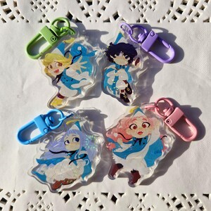 May include: Four clear acrylic keychains featuring anime-style characters in blue and white outfits. Each keychain has a different colored clasp: green, purple, pink, and blue. The characters have varying hair colors, including blonde, purple, and pink.