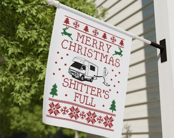 May include: White Christmas flag with a red and green knitted pattern. The flag features a white camper van with a person pulling it. The text on the flag reads "Merry Christmas Shitter's Full".