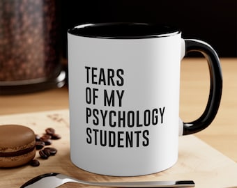 May include: White ceramic coffee mug with a black rim and handle. The mug has black text that reads "Tears of my Psychology Students".
