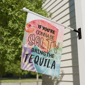 May include: A colorful garden flag with a watercolor background featuring seashells and a cocktail glass. The text on the flag reads "If you're gonna be salty bring the tequila."