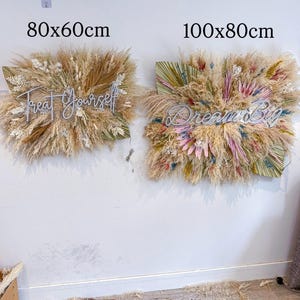 May include: Two wall decorations with dried floral arrangements. One is 31.5 x 23.6 inches, the other is 39.4 x 31.5 inches. The first has the text "Treat Yourself", the second has "Dream Big". Both are mounted on a white wall.