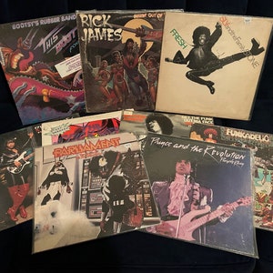 May include: A collection of ten vintage vinyl records by various artists, including Rick James, Parliament, Funkadelic, Prince, and Sly and the Family Stone. The records are in various colors and feature different album covers.