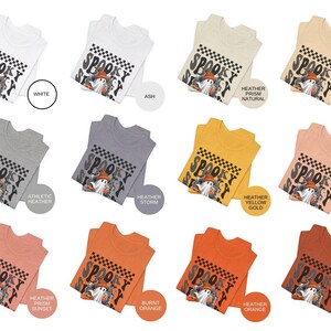 May include: A collection of ten t-shirts featuring a spooky ghost graphic with the text "Spooky Scary" in black and white checkered pattern. The shirts are available in a variety of colors, including white, ash, heather storm, heather yellow gold, heather peach, heather prism natural, burnt orange, heather orange, heather sunset, and heather autumn.