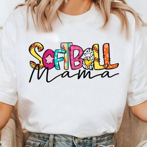 K&ouml;nnte beinhalten: Wei&szlig;es T-Shirt mit einer bunten Grafik, auf der "Softball Mama" steht.