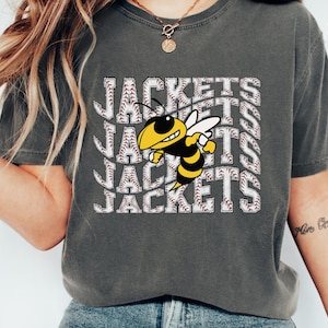 May include: A gray t-shirt with a graphic of a yellow and black bee with the word "JACKETS" repeated in a baseball stitch pattern.