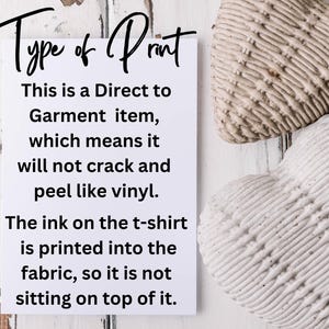 May include: A white card with black text explaining the type of print used on t-shirts. The text reads "Type of Print. This is a Direct to Garment item, which means it will not crack and peel like vinyl. The ink on the t-shirt is printed into the fabric, so it is not sitting on top of it."
