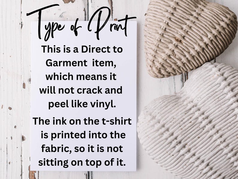 May include: A white card with black text explaining the type of print used on t-shirts. The text reads "Type of Print. This is a Direct to Garment item, which means it will not crack and peel like vinyl. The ink on the t-shirt is printed into the fabric, so it is not sitting on top of it."