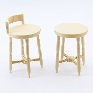 Può includere: Due sgabelli in legno non finiti con gambe tornite e un design semplice. Lo sgabello a sinistra ha uno schienale.