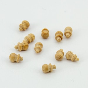 以下が含まれることがあります： さまざまな形とサイズの小さな木製ノブが10個集まったものです。ノブは薄い茶色で、滑らかな仕上がりです。