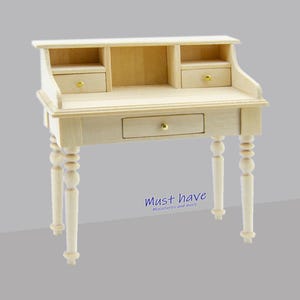 Puede incluir: Un escritorio de madera para casa de muñecas con un cajón y dos estantes. El escritorio tiene patas torneadas y pomos dorados.