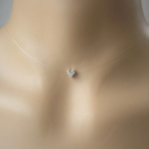 Puede incluir: Un collar invisible con un dije de corazón plateado.