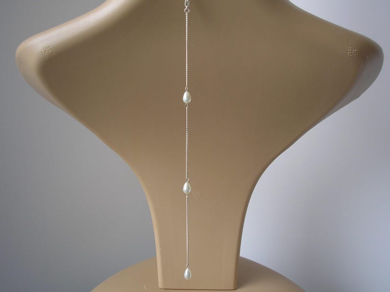 Simple dainty teardrop pearl clip-on backdrop attachment for a necklace.
Handmade to order using 7mm quality glass teardrop pearls on fine silver or gold plated curb chain.
The backdrop will be made to your chosen length and is finished with a little lobster clasp, for easy attachment to your necklace.