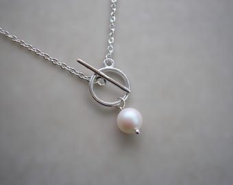 Collana con chiusura frontale a cerchio e barretta in argento, pendente con perla e moschettone a T.