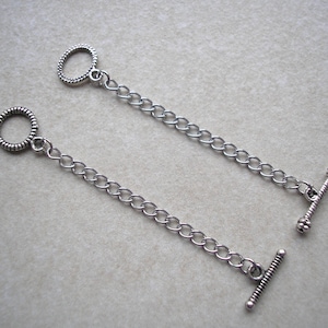 May include: Two silver chain extenders with a t-bar clasp and a round ring at each end.