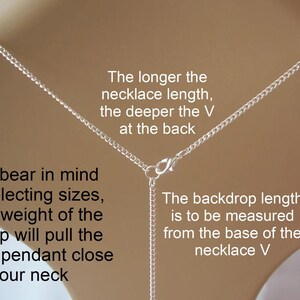 May include: A silver necklace with a V-shaped design, shown against a neutral background. Text explains how the necklace length affects the V shape and how to measure the backdrop length. The text also mentions the weight of the backdrop.