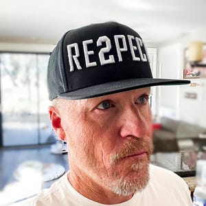 Puede incluir: Una gorra de béisbol negra con la palabra "RE2PECT" bordada en blanco en la parte delantera.