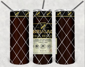 May include: A stainless steel tumbler with a brown and white design featuring the text "BRUGAL" and "DOBLE RESERVA". The design includes a diamond pattern and a label with the text "MEZCLA DE INVE'ECIDOSEN PARRICAS DE WHISKEY-YVINO DE JEREZ RON".