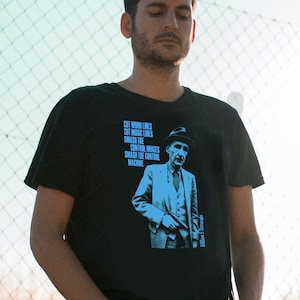 May include: A black t-shirt with a blue graphic of a man in a suit holding a gun. The graphic includes the text "Cut word lines, Cut music lines, Smash the control images, Smash the control machine, William S Burroughs".