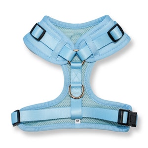 Peut inclure: Un harnais pour chien bleu clair avec un panneau en maille et des sangles r&eacute;glables. Le harnais a un anneau en D en m&eacute;tal et une &eacute;tiquette de taille indiquant "M".
