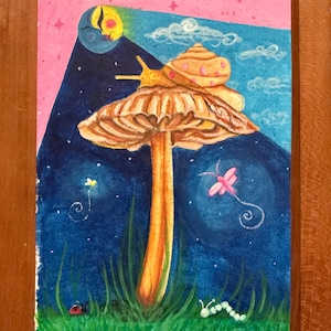 Puede incluir: Pintura enmarcada que muestra un caracol sobre una seta en una escena nocturna. La obra presenta una luna creciente, estrellas y una libélula. La paleta de colores incluye rosa, azul, naranja y verde, creando una ilustración de ensueño y fantasía.