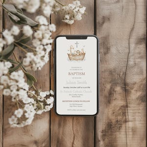 Peut inclure: Un smartphone affiche une invitation de bapt&ecirc;me avec une croix et une illustration d'animaux dans une arche. Le texte de l'invitation est "Veuillez vous joindre &agrave; nous pour c&eacute;l&eacute;brer le bapt&ecirc;me de notre fils, Julian Smith."