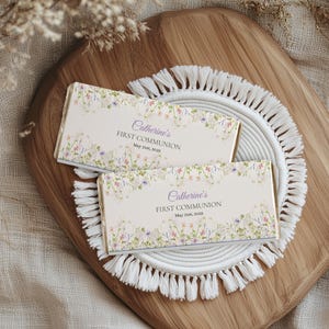 Puede incluir: Dos barras de chocolate blanco con diseños florales y el texto "Catherine's First Communion May 21st, 2023".