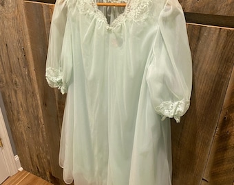 May include: A light blue sheer nightgown with lace trim around the neckline and sleeves. The gown is hanging on a wooden hanger.