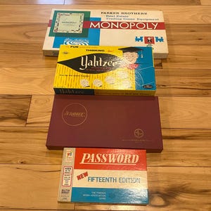 May include: A collection of vintage board games including Monopoly, Yahtzee, Scrabble, and Password. The games are in their original boxes and are in good condition.