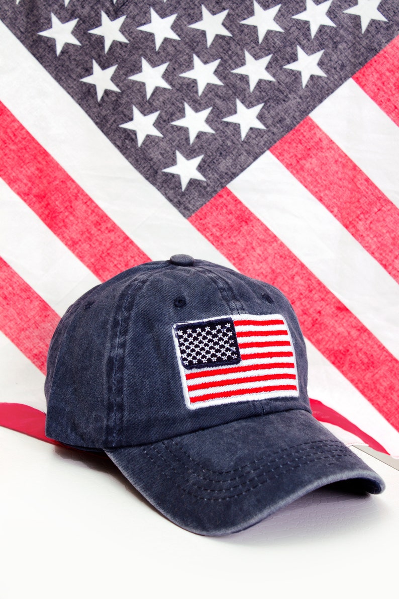 May include: A dark blue baseball cap with a red, white, and blue American flag embroidered on the front.