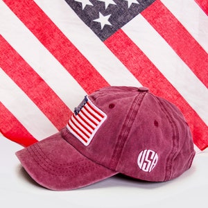 May include: A burgundy baseball cap with a small American flag patch and a white embroidered "USA" on the back.
