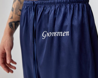 May include: Navy blue satin pajama pants with a drawstring waist and the word "Groomsmen" embroidered in white.