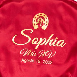 A red satin robe with gold text and a horseshoe logo on the back.