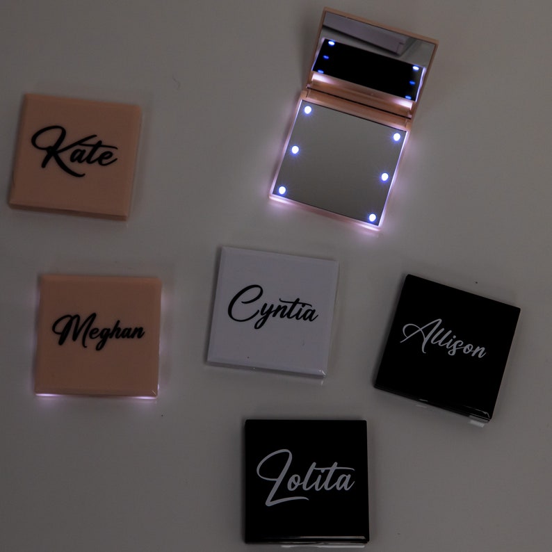 May include: Five small, square, compact mirrors with LED lights. Each mirror has a different name on the front: Kate, Meghan, Cynthia, Allison, and Lolita. The mirrors are in various colors: pink, white, and black.