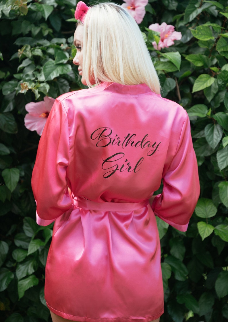 May include: Pink satin robe with a black inscription that reads "Birthday Girl".