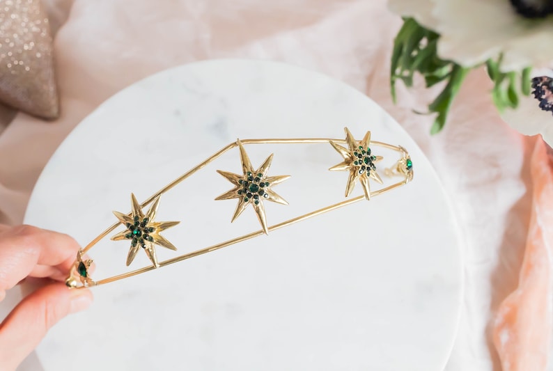 May include: Gold headband with a row of five green jeweled starbursts.