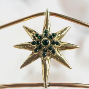 May include: A gold star-shaped ornament with green gem accents.