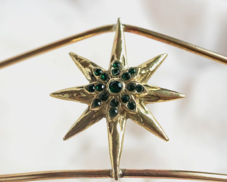 May include: A gold star-shaped ornament with green gem accents.
