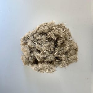 May include: A close-up of a pile of light brown flax fibers. The fibers are soft and fluffy, and they are perfect for use in a variety of crafts.
