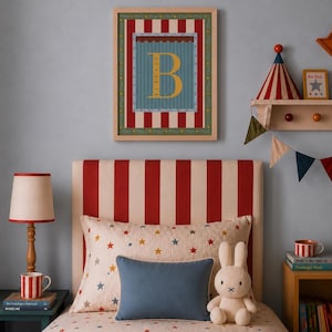 Op de afbeelding: Een ingelijste wandprint met een grote gele letter B gecentreerd op een blauwe achtergrond met rode en witte verticale strepen. De print hangt boven een bed met een rood-wit gestreept hoofdeinde en beddengoed met sterrenpatroon.