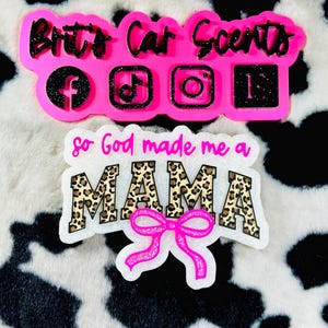May include: Two car air fresheners. The top one is pink with black glitter text that reads "Britt's Car Scents" and social media icons. The bottom one is white with leopard print text that reads "so God made me a MAMA" with a pink bow.
