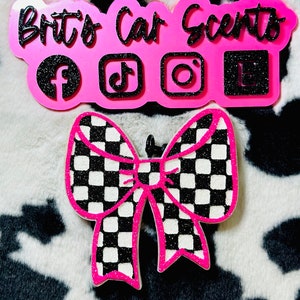May include: Pink car air freshener with a black and white checkered bow and the text "Brit's Car Scents" with social media icons.