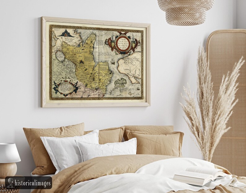 May include: A framed vintage map with a light wood frame. The map features a detailed illustration with shades of yellow, brown, and blue. Ornate cartouches and text are visible. The map is displayed above a bed with neutral-toned bedding.