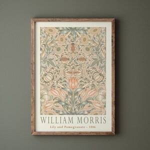 K&ouml;nnte beinhalten: Ein gerahmter Druck eines Vintage-Blumenmusters mit gelbem Hintergrund, gr&uuml;nen und blauen Bl&auml;ttern und rosa Bl&uuml;ten. Der Druck ist mit "William Morris, Lily and Pomegranate - 1886" betitelt.
