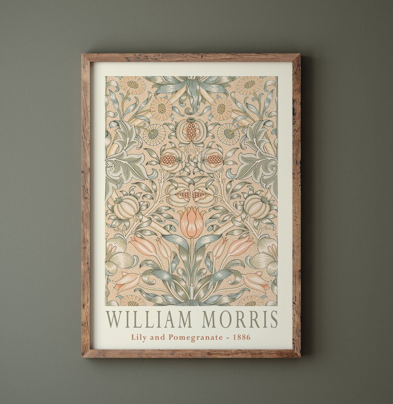 K&ouml;nnte beinhalten: Ein gerahmter Druck eines Vintage-Blumenmusters mit gelbem Hintergrund, gr&uuml;nen und blauen Bl&auml;ttern und rosa Bl&uuml;ten. Der Druck ist mit "William Morris, Lily and Pomegranate - 1886" betitelt.