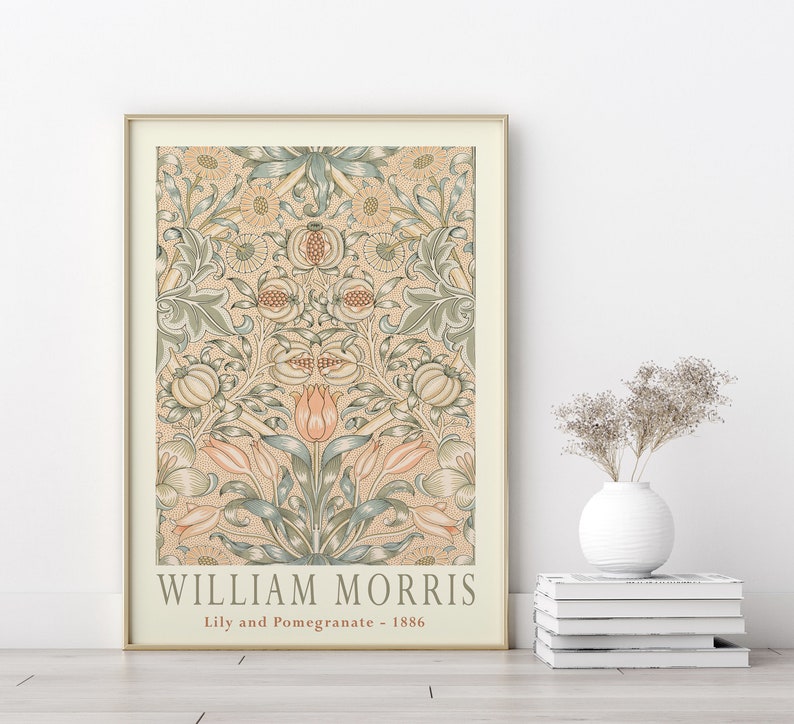 K&ouml;nnte beinhalten: Ein gerahmter Druck eines Vintage-Blumendesigns von William Morris, mit einem sich wiederholenden Muster aus Lilien und Granat&auml;pfeln in Gr&uuml;n-, Rosa- und Cremet&ouml;nen. Der Druck tr&auml;gt den Titel "Lily and Pomegranate - 1886".