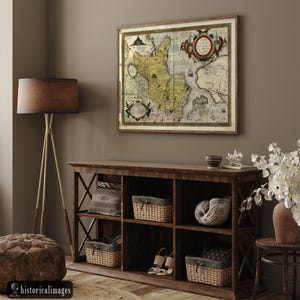 May include: A framed antique map with a detailed cartographic design in shades of yellow, brown, and beige hangs above a dark wooden cabinet. The cabinet features woven baskets, decorative items, and a pair of sandals. A floor lamp and ottoman are also visible.