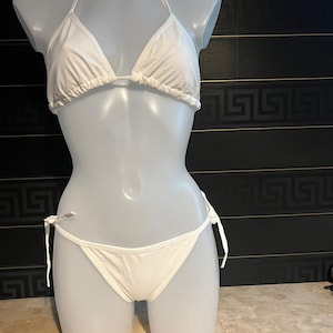 Op de afbeelding: Witte bikini top en broekje met verstelbare bandjes. De top is van het driehoekstype en het broekje is van het type met zijbandjes.